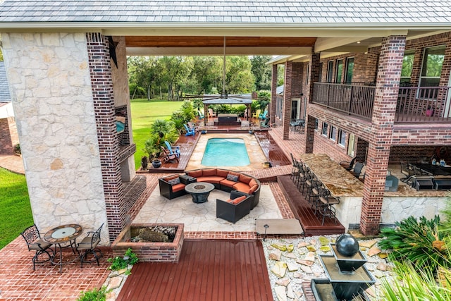 view of pool featuring a yard, a patio, and an outdoor living space with a fire pit