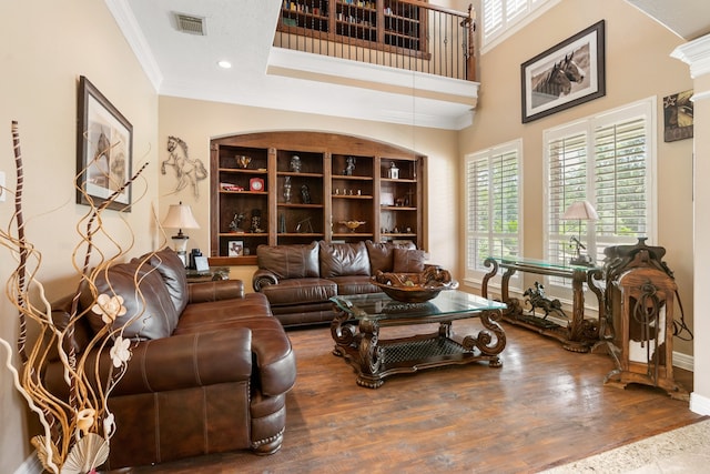 living room with a towering ceiling, ornamental molding, and hardwood / wood-style floors