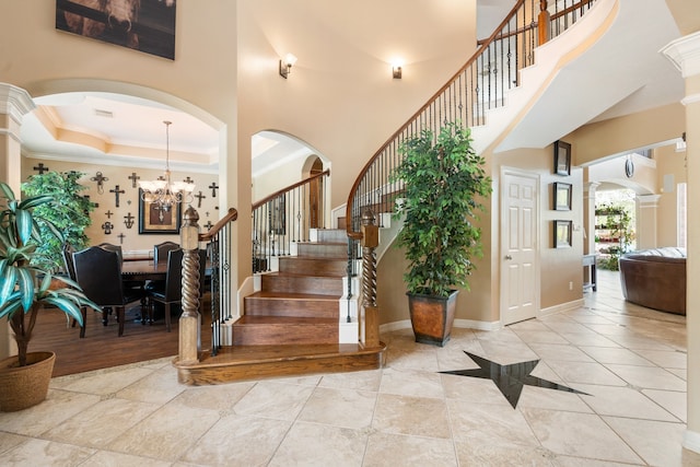 entrance foyer featuring ornate columns, crown molding, a chandelier, and a high ceiling