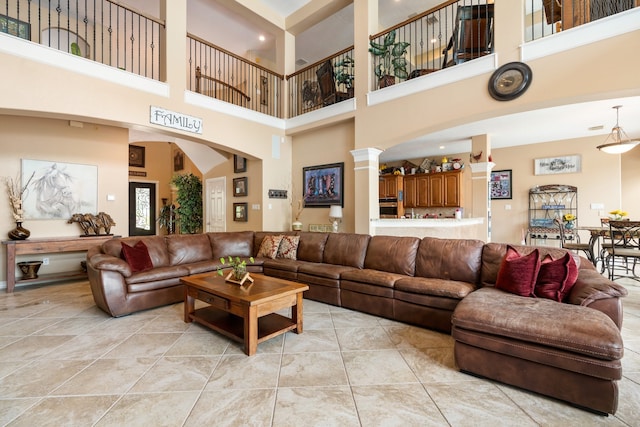 tiled living room featuring a towering ceiling and ornate columns