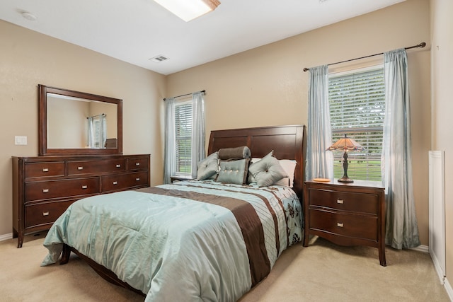 bedroom featuring light colored carpet and multiple windows