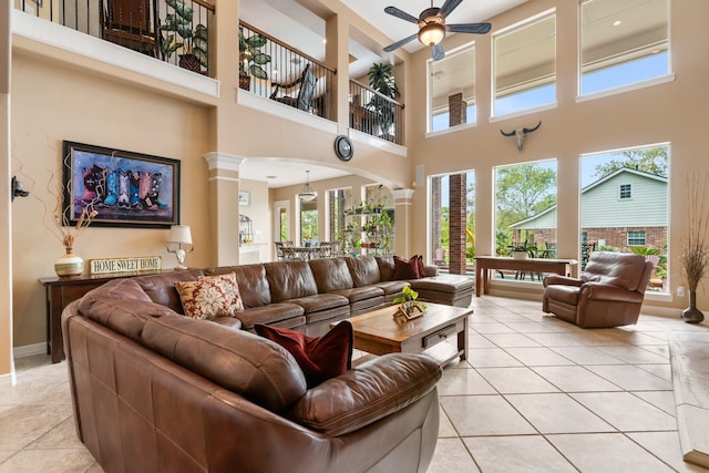 tiled living room featuring ornate columns, a high ceiling, and ceiling fan