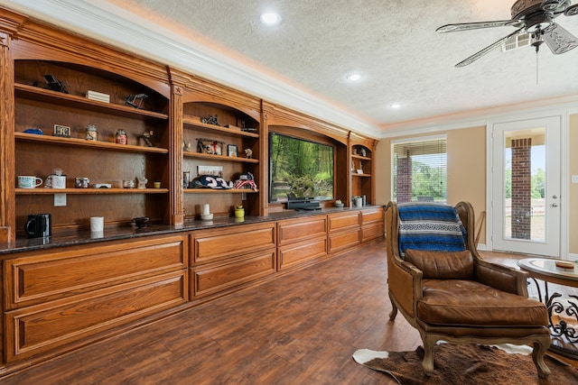 interior space featuring ceiling fan, built in features, ornamental molding, a textured ceiling, and dark hardwood / wood-style floors