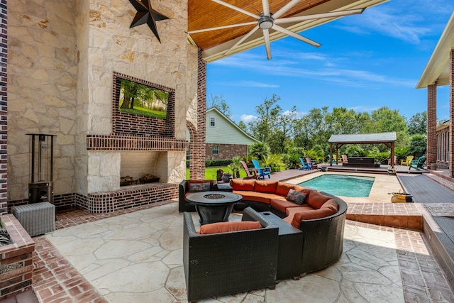 view of patio featuring an outdoor living space with a fireplace, a gazebo, and ceiling fan