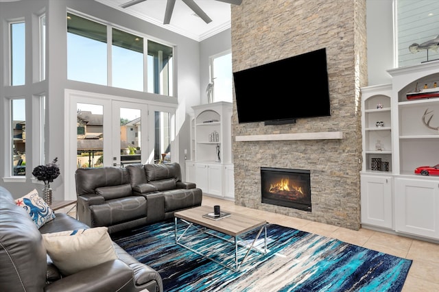 tiled living room with a stone fireplace, a high ceiling, ornamental molding, and a healthy amount of sunlight