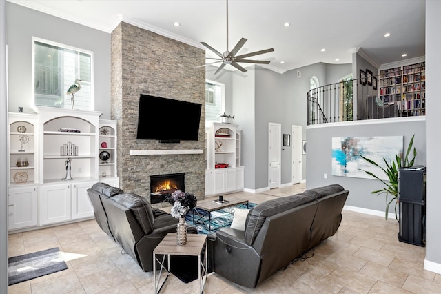 tiled living room with a towering ceiling, crown molding, ceiling fan, and a stone fireplace