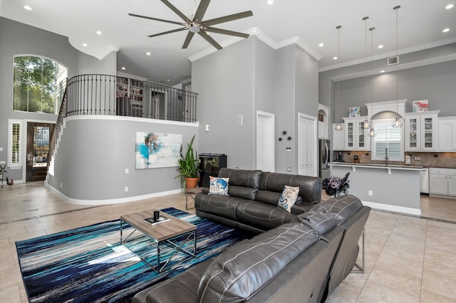 tiled living room featuring a towering ceiling, a wealth of natural light, and ceiling fan