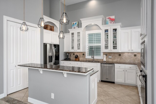 kitchen featuring a kitchen island, stainless steel appliances, sink, pendant lighting, and white cabinetry