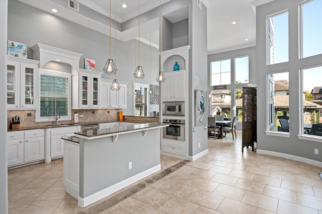 kitchen with appliances with stainless steel finishes, sink, a towering ceiling, and white cabinets