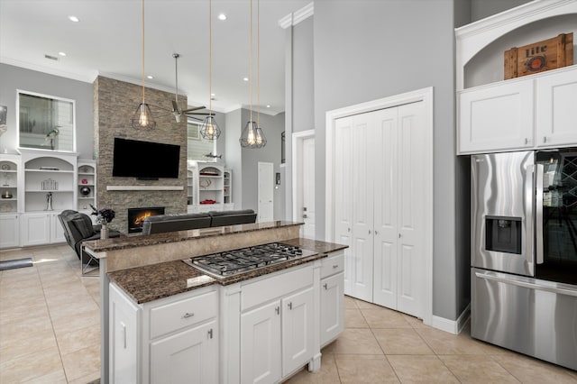 kitchen with a center island, dark stone countertops, stainless steel appliances, light tile patterned floors, and white cabinetry