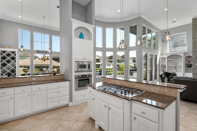 kitchen featuring white cabinets, light tile patterned floors, decorative light fixtures, appliances with stainless steel finishes, and crown molding