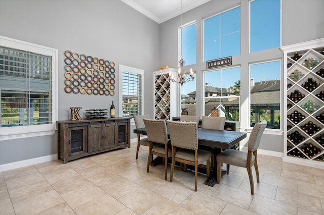 dining room featuring a notable chandelier, a wealth of natural light, a towering ceiling, and crown molding