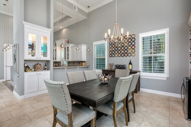 tiled dining space with a towering ceiling, a chandelier, and crown molding