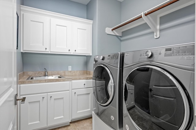 washroom featuring light tile patterned flooring, cabinets, separate washer and dryer, and sink