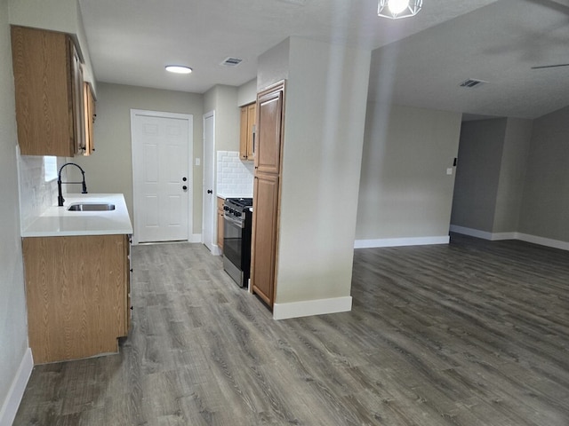 kitchen with gas range, sink, dark hardwood / wood-style flooring, and tasteful backsplash