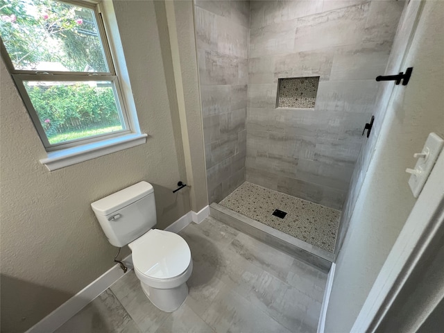 bathroom featuring a tile shower and toilet