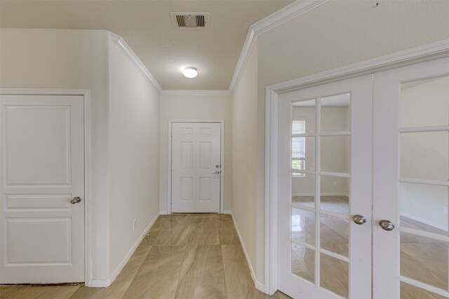 hall with a textured ceiling, crown molding, and french doors