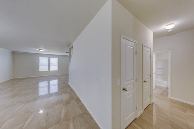 corridor with light tile patterned floors and a textured ceiling