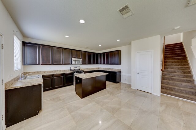 kitchen featuring dark brown cabinetry, sink, a kitchen island, and appliances with stainless steel finishes