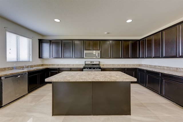 kitchen with dark brown cabinetry, sink, a kitchen island, and appliances with stainless steel finishes