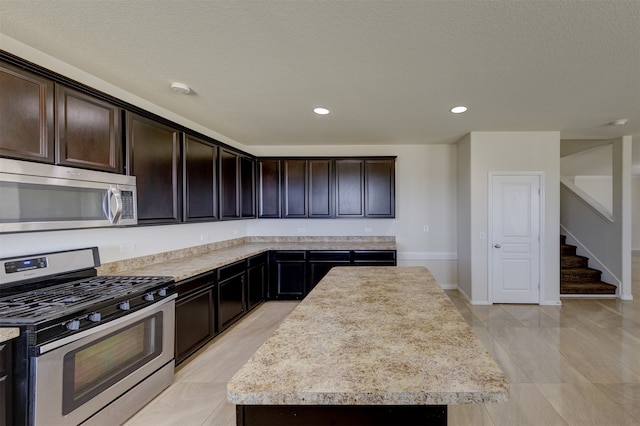 kitchen featuring appliances with stainless steel finishes, a center island, a textured ceiling, and dark brown cabinets