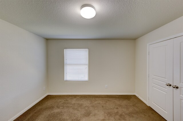 empty room with carpet flooring and a textured ceiling