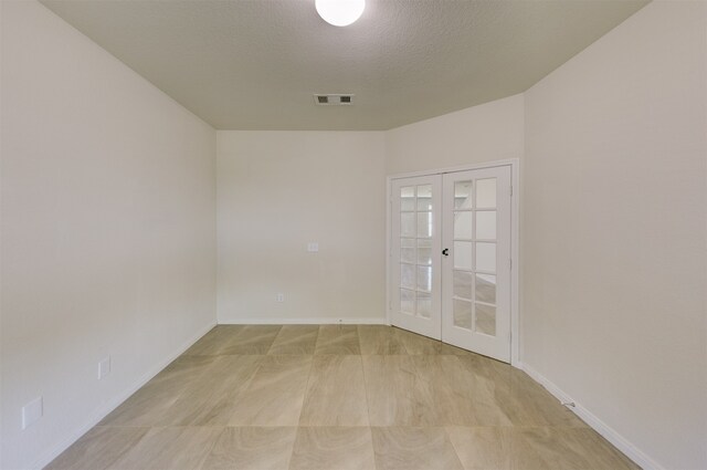 spare room featuring a textured ceiling and french doors