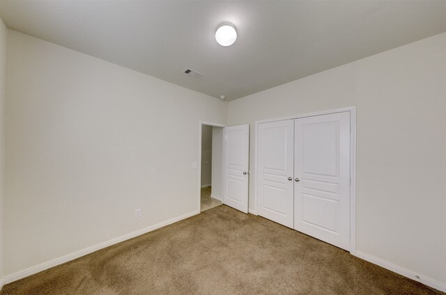 unfurnished bedroom featuring vaulted ceiling, light colored carpet, and a closet