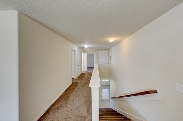 corridor with carpet and a textured ceiling