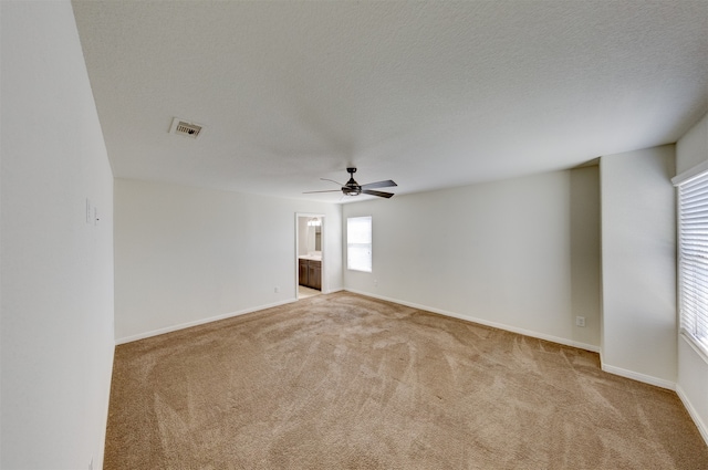 spare room with ceiling fan, light colored carpet, and a textured ceiling