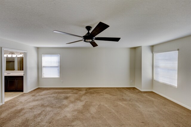 empty room featuring ceiling fan, light colored carpet, and a textured ceiling