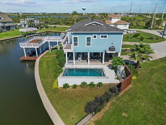 rear view of house featuring a yard, a pool side deck with water view, and a patio area