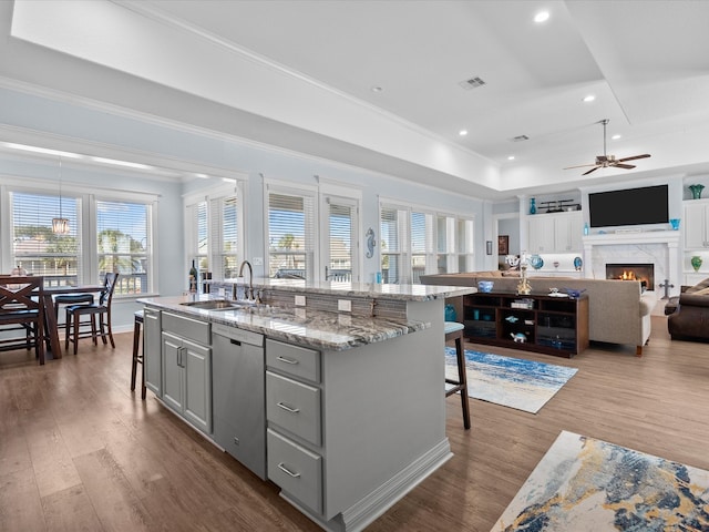 kitchen featuring a healthy amount of sunlight, a kitchen island with sink, a kitchen breakfast bar, and stainless steel dishwasher