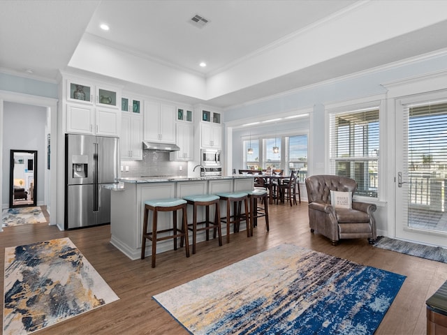 living room with dark wood-type flooring, ornamental molding, sink, and a raised ceiling