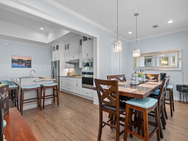 dining area featuring crown molding, sink, and light wood-type flooring