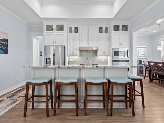 kitchen with white cabinets, appliances with stainless steel finishes, light wood-type flooring, and ornamental molding