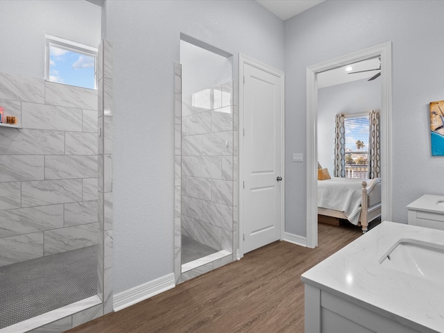 bathroom featuring vanity, hardwood / wood-style flooring, plenty of natural light, and tiled shower