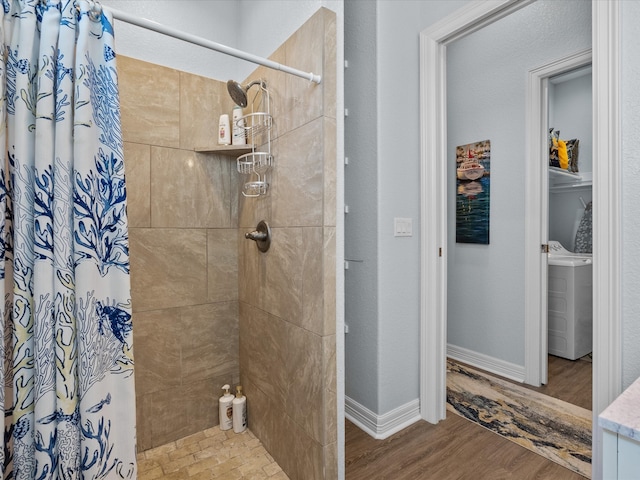 bathroom with wood-type flooring, a shower with curtain, and washer / dryer