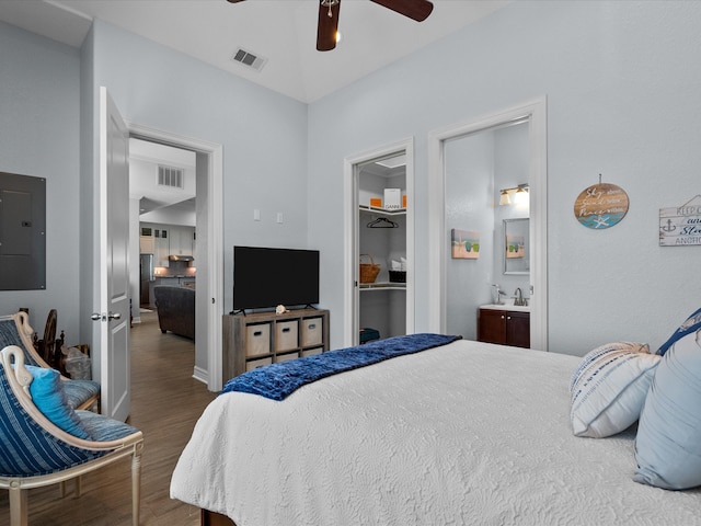 bedroom featuring ceiling fan, hardwood / wood-style flooring, sink, electric panel, and ensuite bath