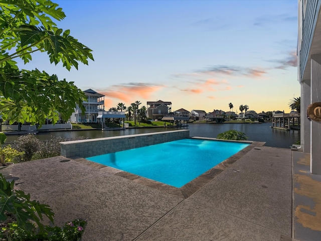 pool at dusk with a water view and a patio