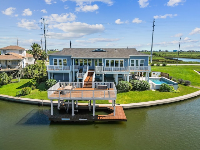 rear view of property featuring a yard, a balcony, and a deck with water view