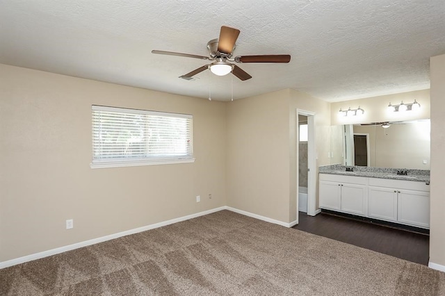 unfurnished bedroom with dark colored carpet, sink, connected bathroom, and ceiling fan