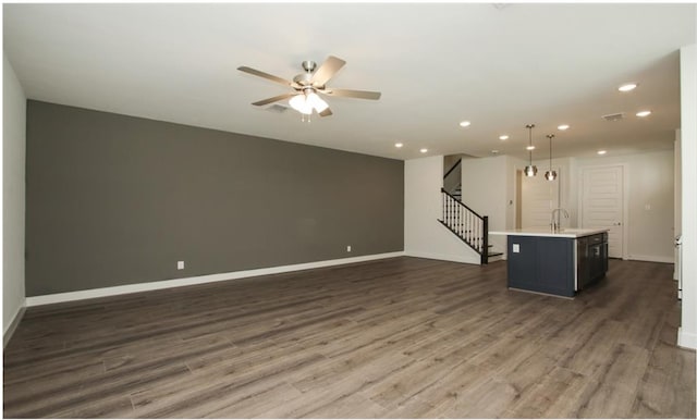 unfurnished living room featuring dark hardwood / wood-style floors, sink, and ceiling fan