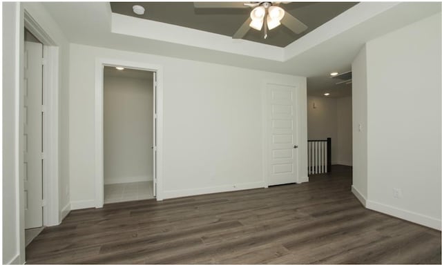 empty room featuring ceiling fan, dark hardwood / wood-style floors, and a raised ceiling