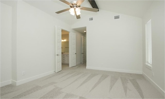 unfurnished bedroom with light colored carpet, lofted ceiling with beams, ensuite bathroom, and ceiling fan