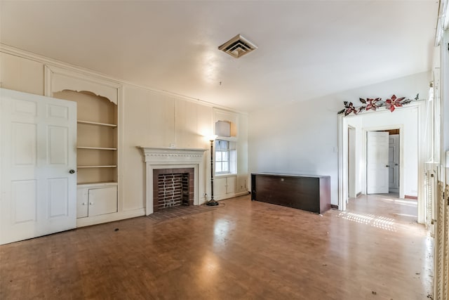 unfurnished living room featuring wood-type flooring, a fireplace, and built in features