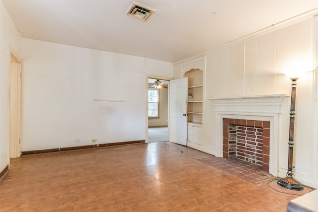 unfurnished living room with ceiling fan and a tiled fireplace