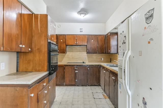 kitchen with decorative backsplash, black appliances, and sink