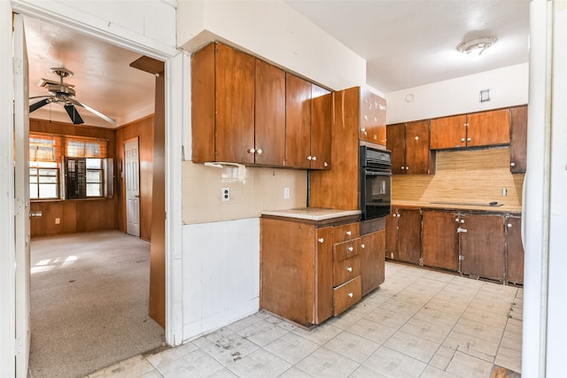 kitchen featuring wood walls, ceiling fan, light carpet, decorative backsplash, and black appliances