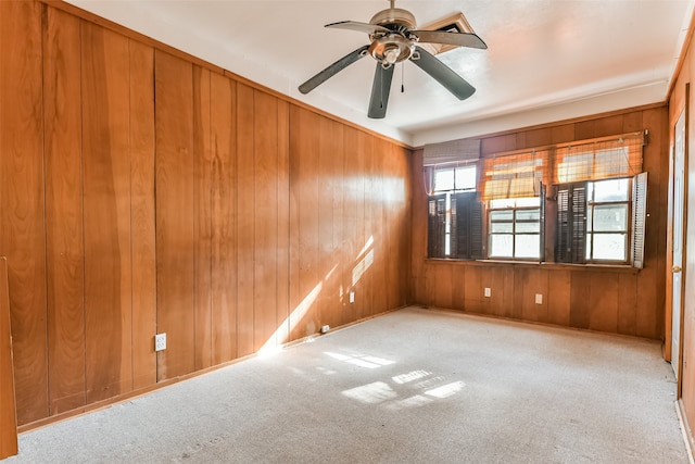 carpeted empty room with wooden walls and ceiling fan